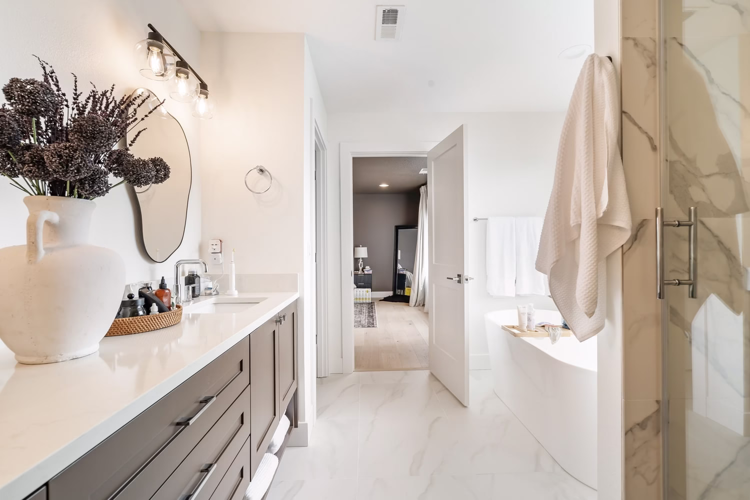 Primary bath looking down the vanity run to a freestanding tub, with a glass shower enclosure to the right