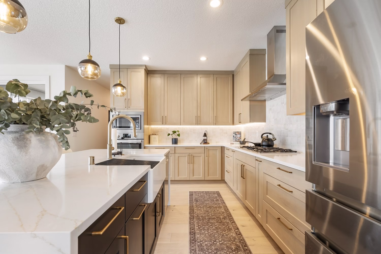 Kitchen island with waterfall edge and apron-front sink, gas cooktop and chimney hood behind