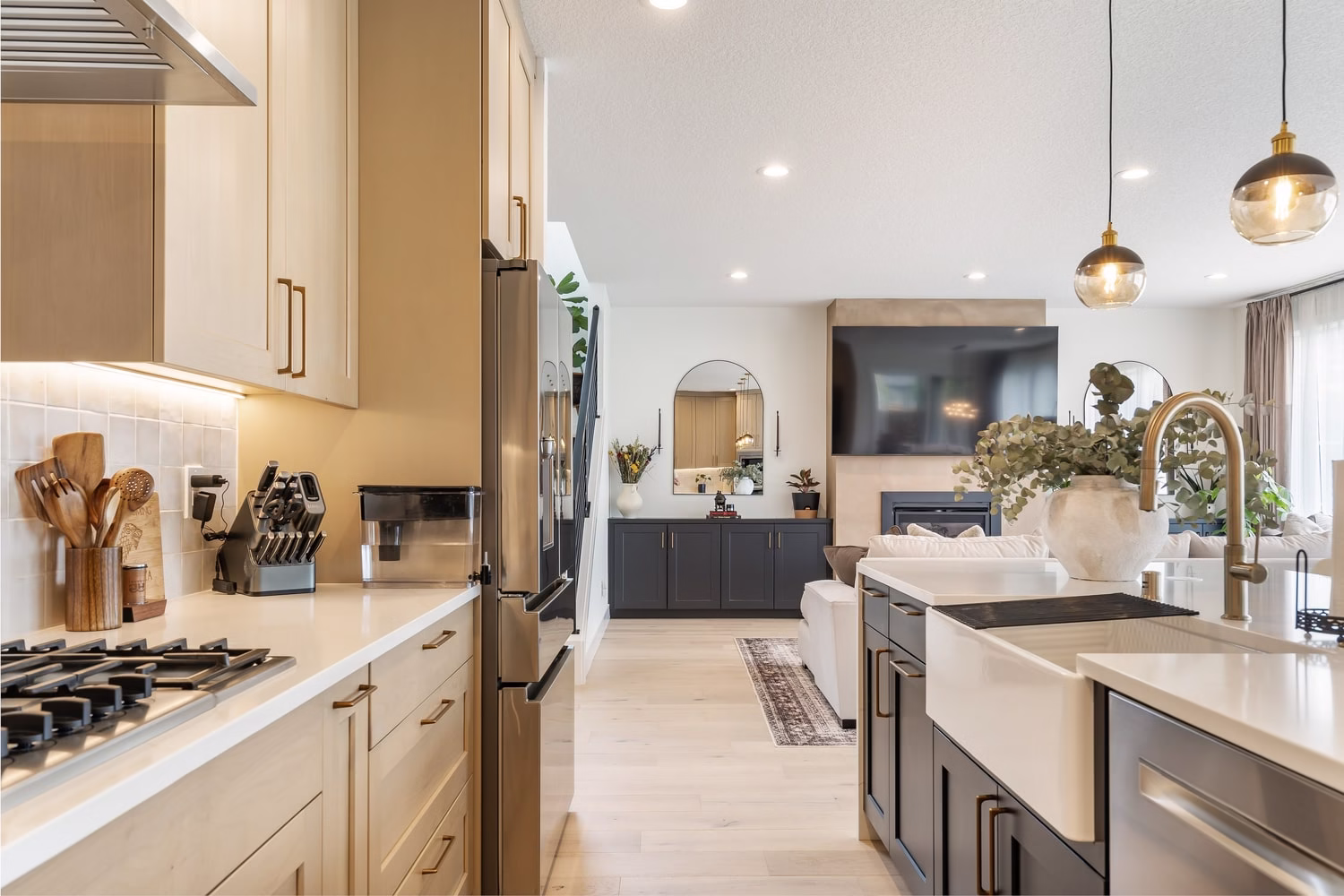 View along a kitchen run through to the living room, with apron-front sink, gooseneck faucet and a fireplace wall beyond
