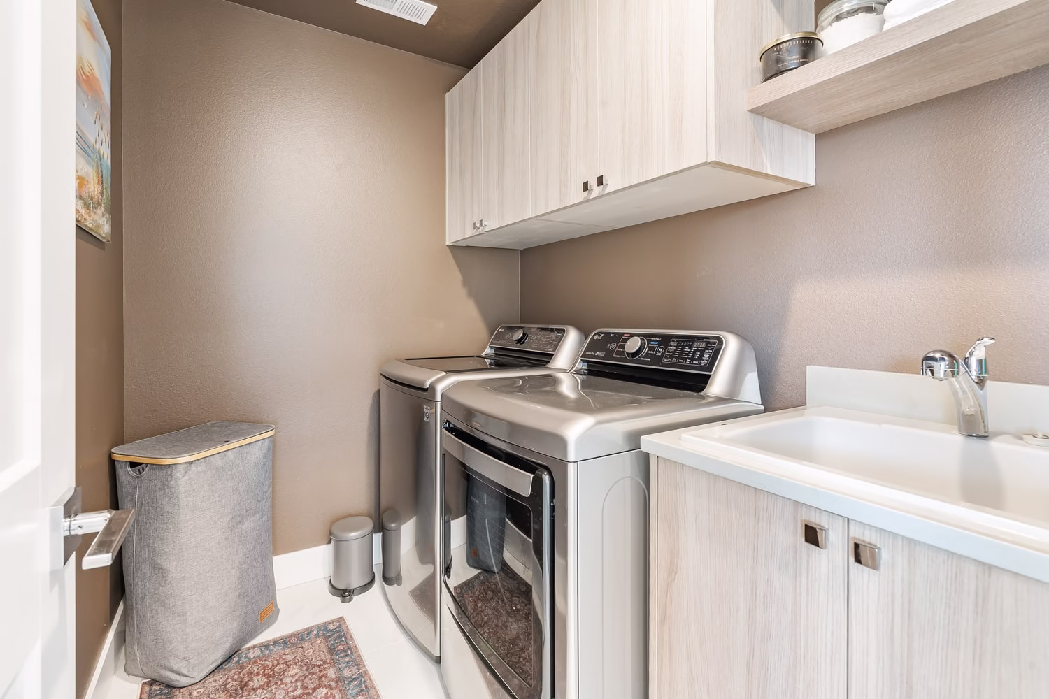 Laundry room with upper cabinetry, an open shelf, a utility sink and side-by-side machines